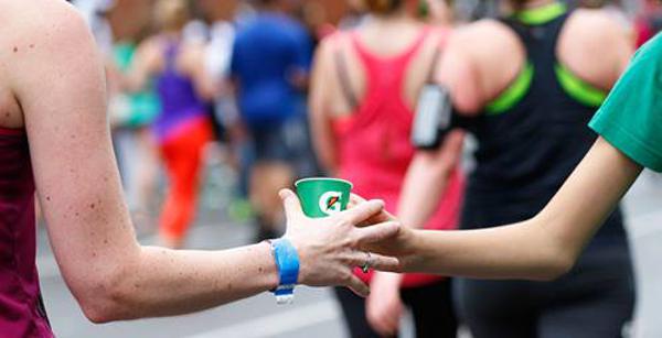 one runner passing a gatorade cup to another