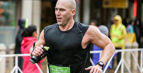 Bald man running while holding a water bottle