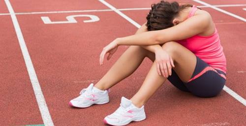 Runner sitting on the track with her head in between her knees