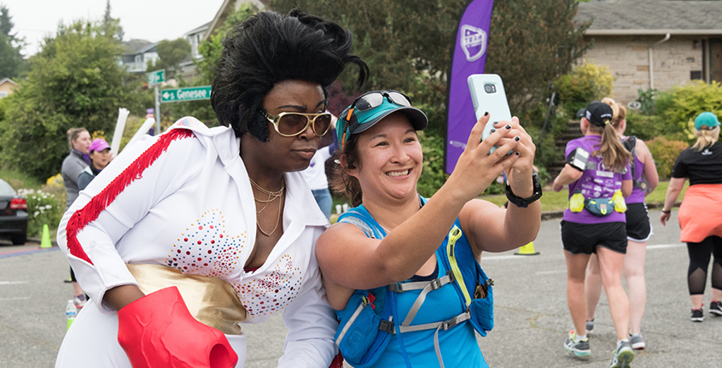 a woman taking a selfie with an elvis impersonator runner